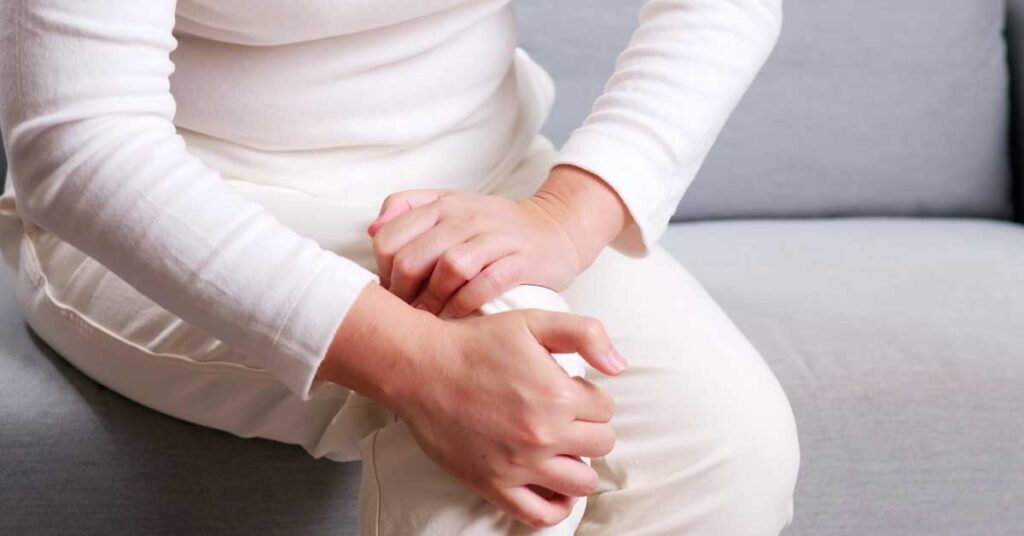 woman holding leg after dealing with chronic pain