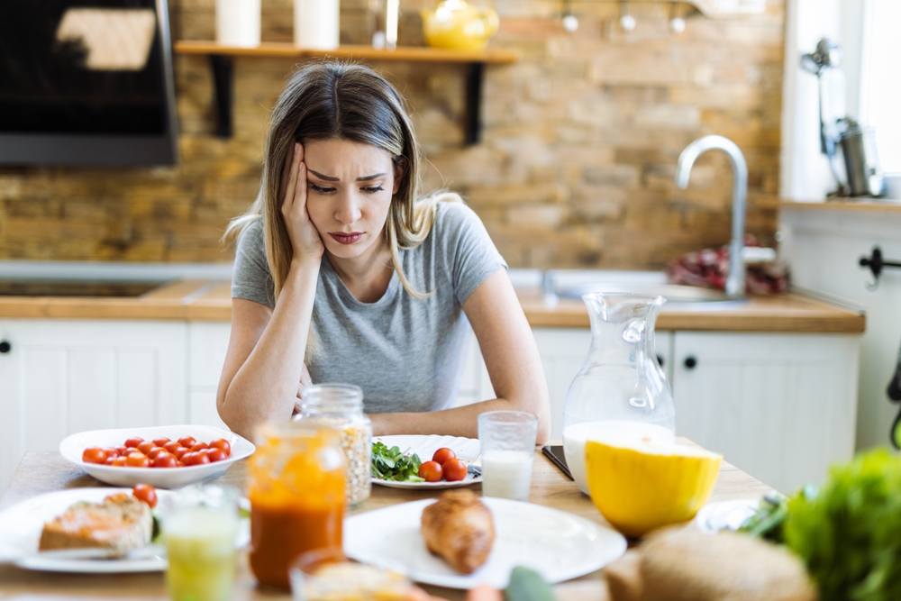 Depressed young woman doesn't want to eat her breakfast